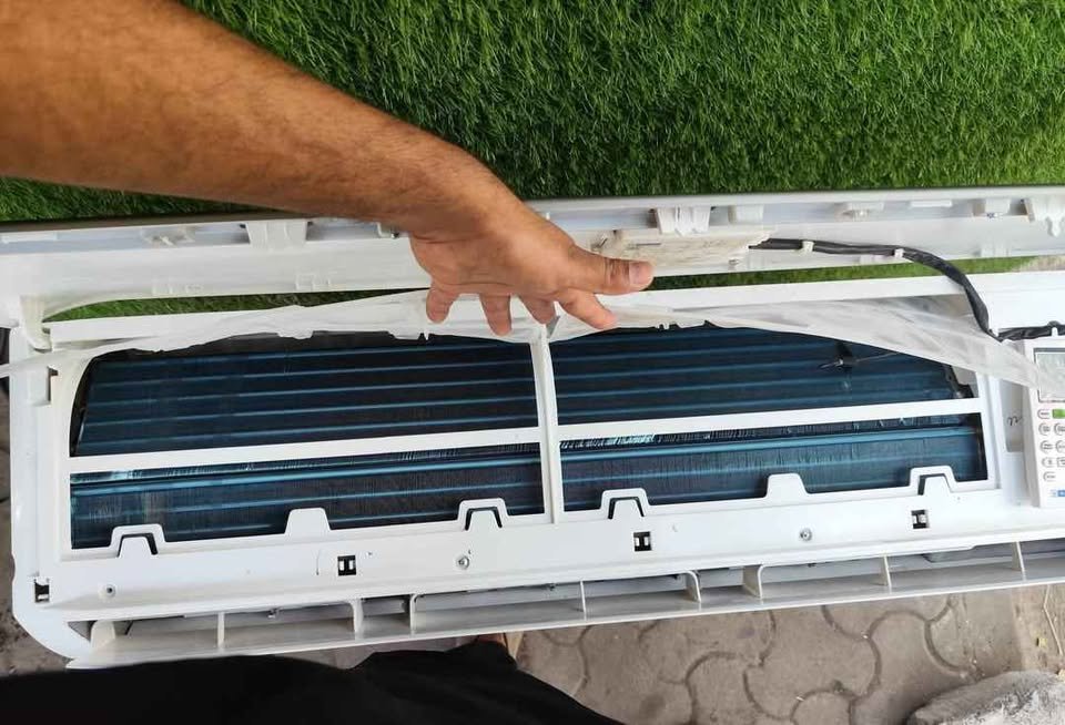 Person cleaning a Blue Star split AC indoor unit filter for improved cooling efficiency